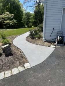 Curved stamped concrete walkway leading to a landscaped entrance